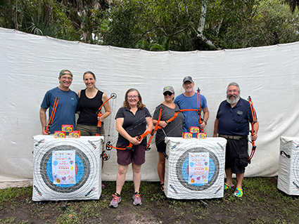 people with archery bows posing for a photo in front of archery targets